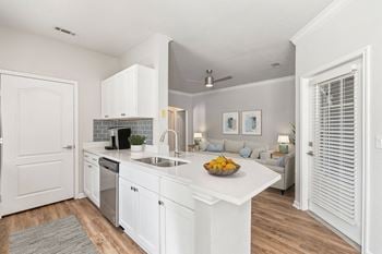 A kitchen with white cabinets and a bowl of fruit on the counter